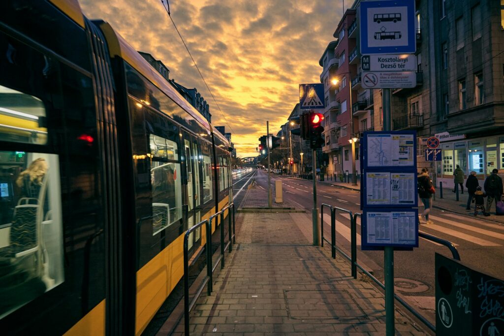 a yellow and black train some buildings and people